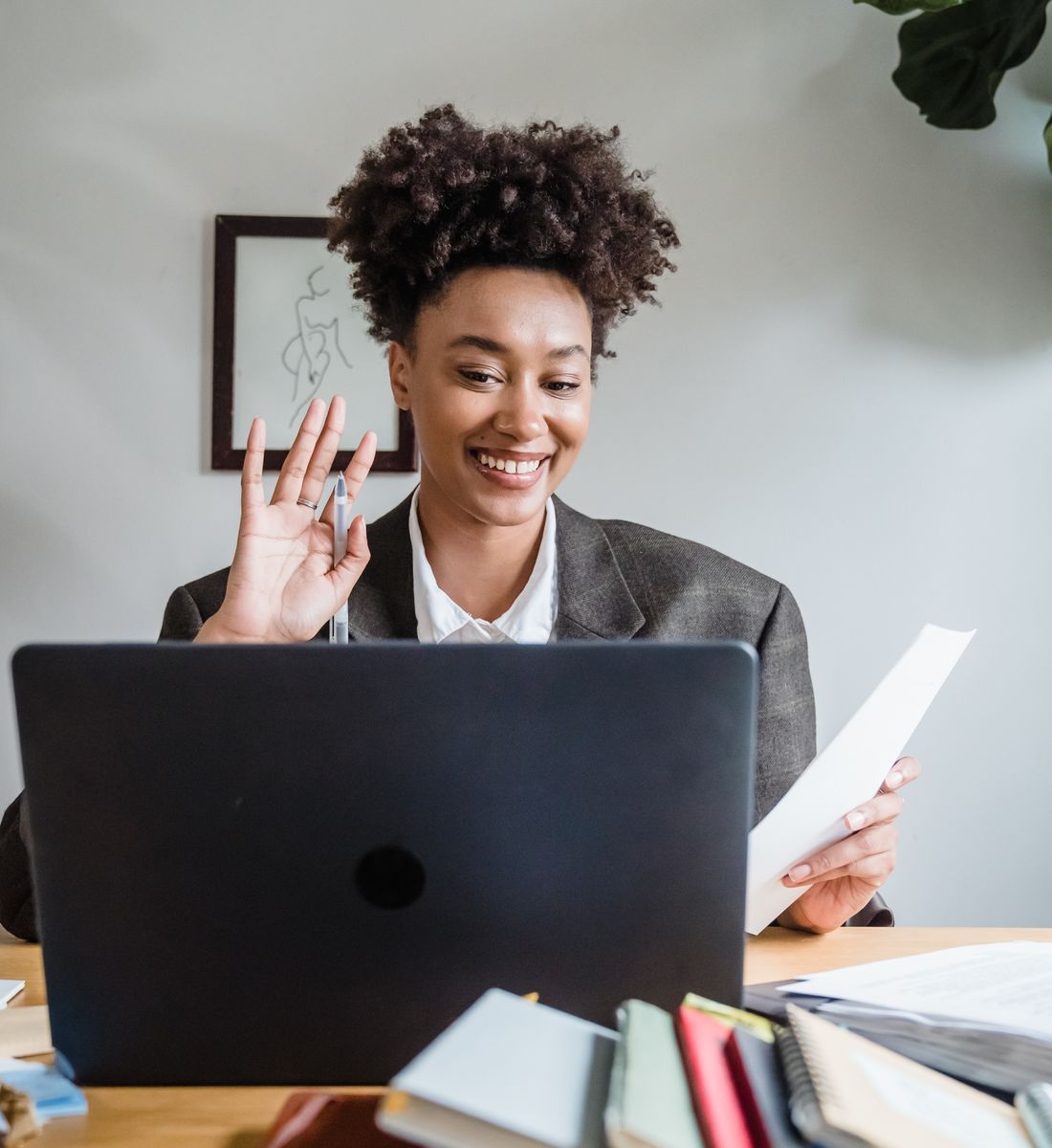 A woman waving at her laptop during a call from home
